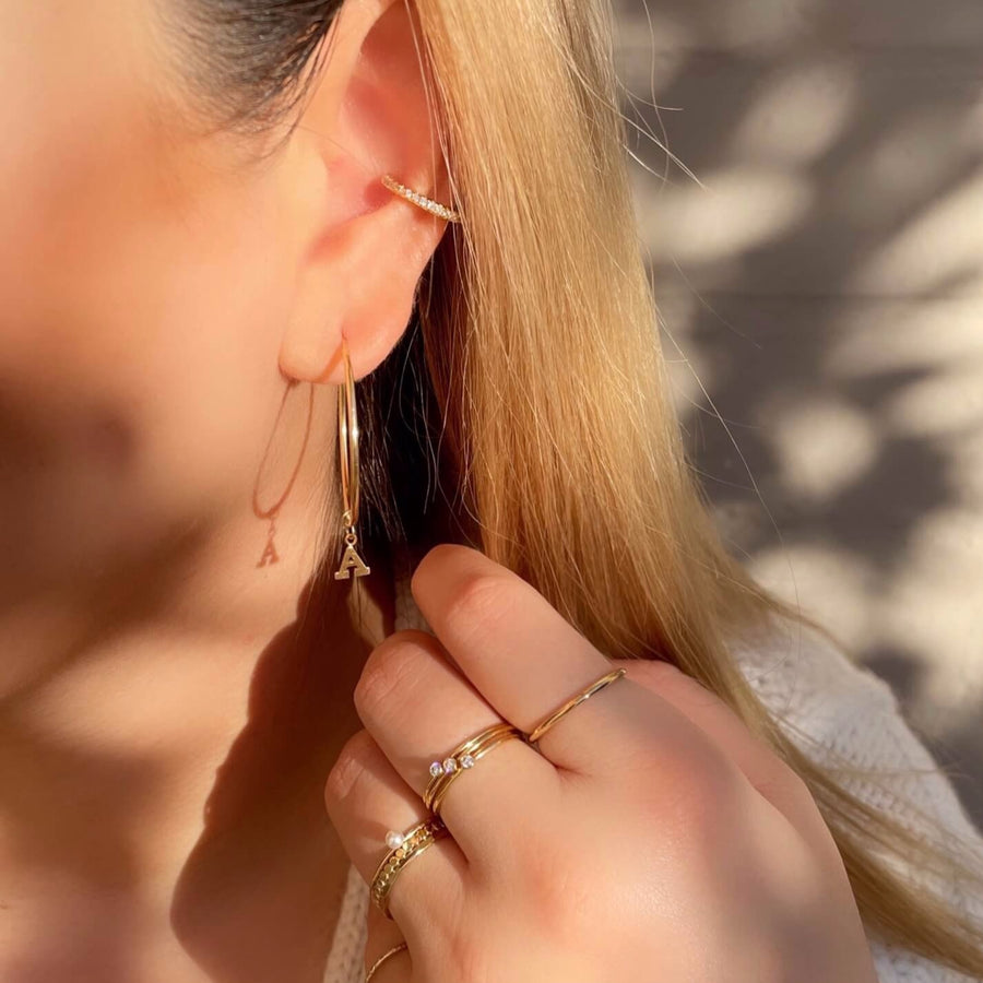 Model Wearing Ale Weston Endless Hoop Earrings 30mm Gold Letter Charm Eternity Ear Cuff Stacker Rings