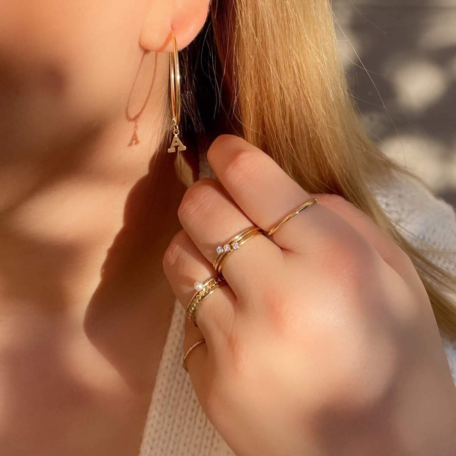 Model-Wearing-Ale-Weston--Endless-Hoop-Earrings-33mm-and-Gold-Letter-Charm-(A)-and-Stacker-Rings-Thick-Stacker-Ring-Gold-Dots-Rings-Hammered-Stacker-Ring-Sparkle-Stacker-Ring-Pearl-Stacker-Ring-Mini-CZ-Stacker-Ring